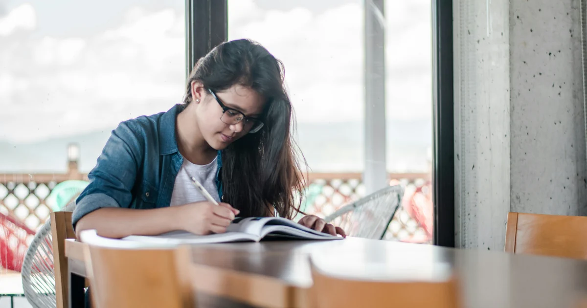 A woman writes in an open book.