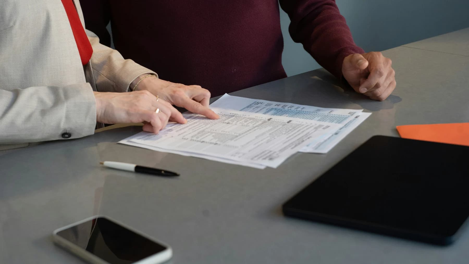 Two people review paperwork together at a table.